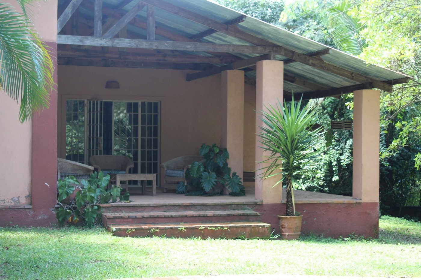 Pool Cottage exterior with covered veranda, pillars, and palm tree