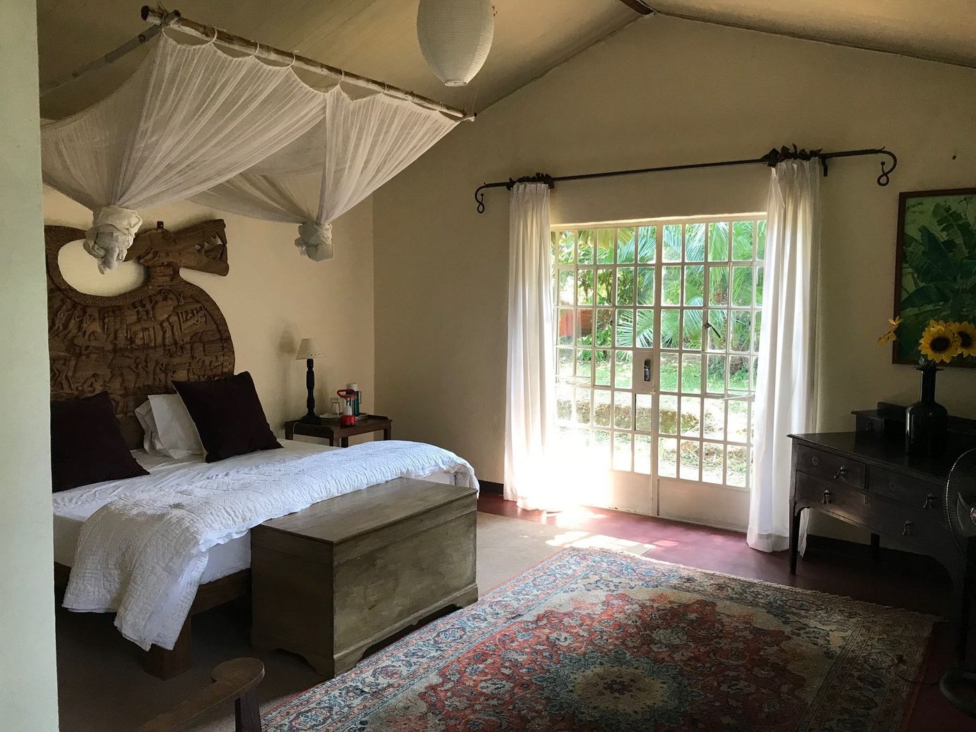 Heritage suite bedroom with carved African headboard and mosquito net