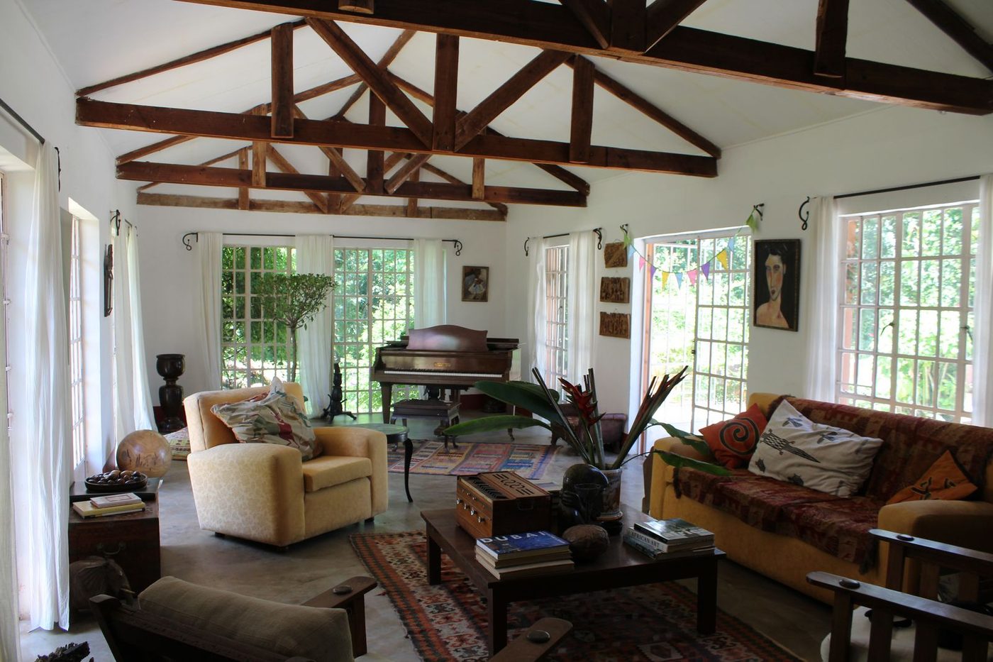 Grand sitting room with exposed beam ceiling, piano, armchairs, and kilim rugs